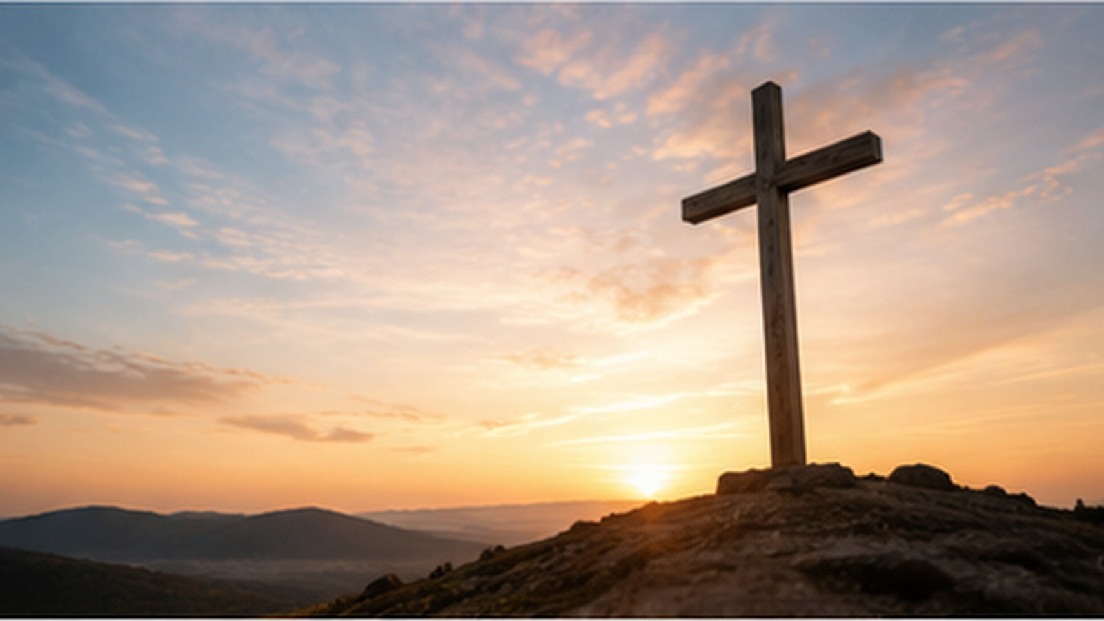 A wooden cross on a hill at sunrise