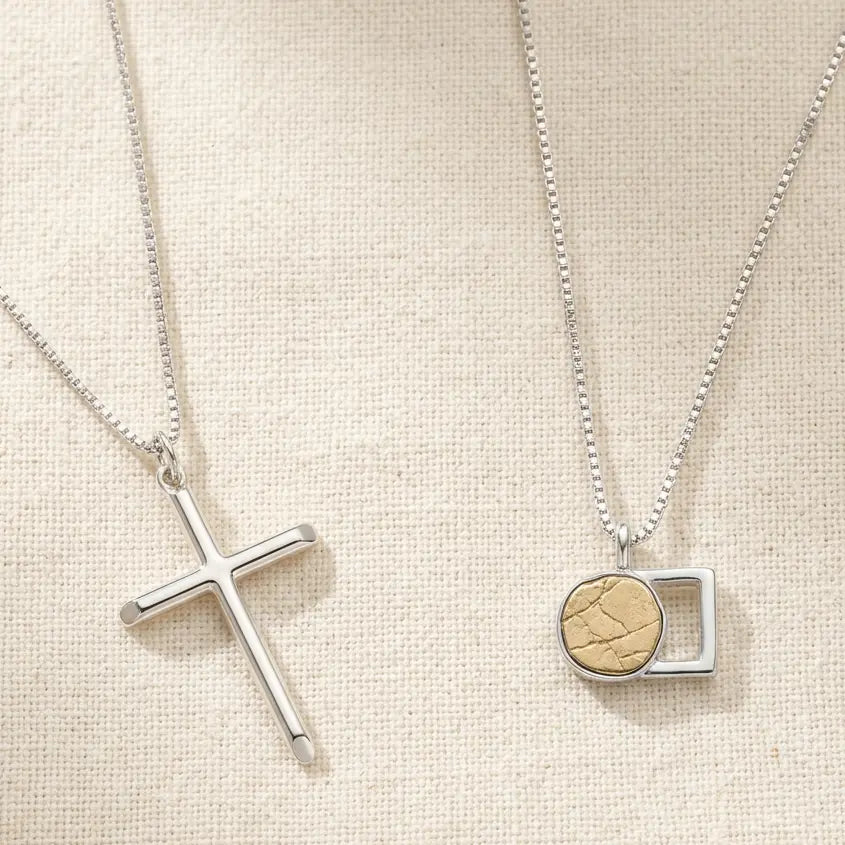 A silver cross necklace beside The Empty Tomb Necklace